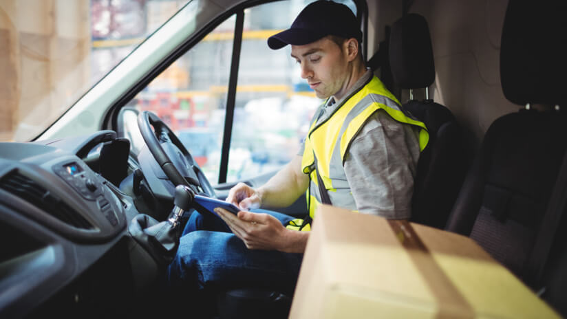 Delivery driver in van, looking at the orders on his tablet